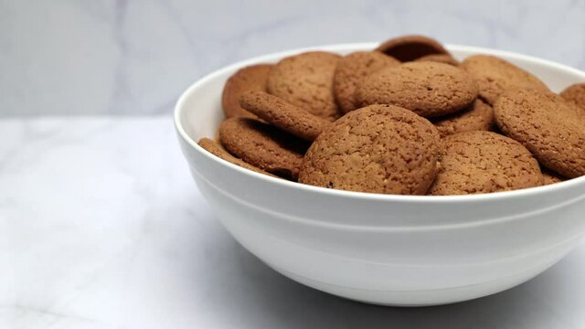 Fresh Brown Oatmeal Cookies With Sugar In A White Bowl On A White Kitchen Background. Panning Slider Shot.