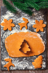 The process of making Christmas Ginger cookies. A Christmas tree-shaped mold on a raw dough for gingerbread cookies