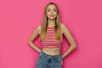 Cheerful Young Woman In Striped Tank Top Is Posing Against Pink Background