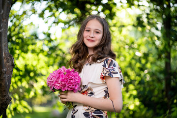 cheerful girl in a light summer dress against the background of a city park