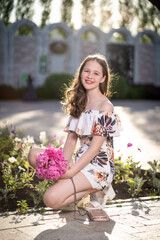 Naklejka premium cheerful girl in a light summer dress against the background of a city park