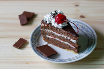 chocolate cake in dish.It was decorated with cream and cherry.It is sweet and yummy.But it is not good for health.