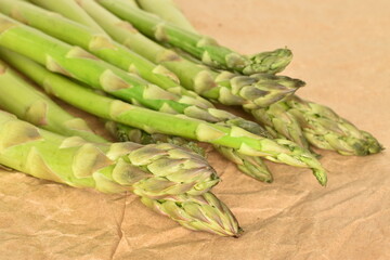 Several stalks of ripe organic asparagus on craft paper, close-up.