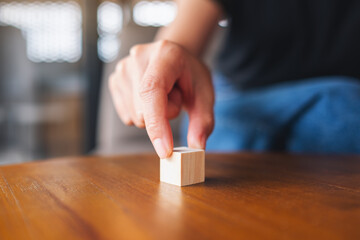 Closeup image of a hand choosing and picking a piece of blank wooden cube block