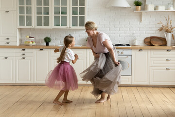 Full length happy barefoot 7s cute little kid girl and older retired grandmother wearing puffy...