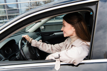 pretty young woman smiling while driving car in city