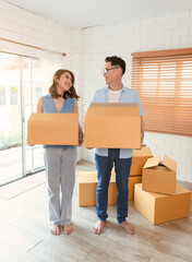 Fototapeta na wymiar Happy Asian couple holding cardboard box go into new home. Relocation concept.