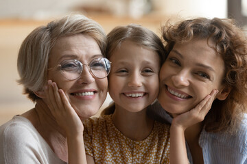 Head shot close up portrait of sincere emotional happy three female generations bonding family...