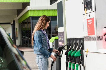 smiling woman taking fuel pistol on gasoline station