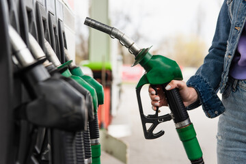 cropped view of woman holding petrol pistol on gas station