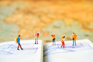 Miniature people: Group of traveler mini figures with backpack stand and walking on passport with stamps. Success Business Due around the world and Travelling agency concepts.