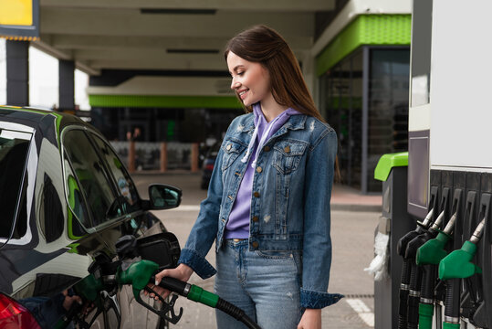 Smiling Woman In Denim Clothes Fueling Car On Gas Station