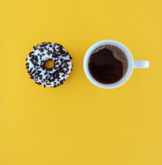 donut and coffee cup on yellow background, breakfast sweets