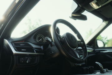 Fototapeta na wymiar Black premium car interior. Dashboard, steering wheel, speedometer at sunny day