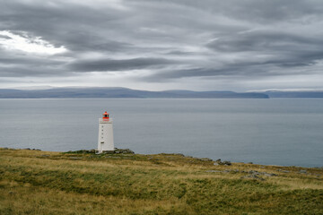 Fototapeta na wymiar Lighthouse on the cliff near the ocean in Northwest Iceland