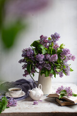 Bouquet of lilacs in a vintage basket. Beautiful violet Lilac flower still life Easter border design on wooden table.