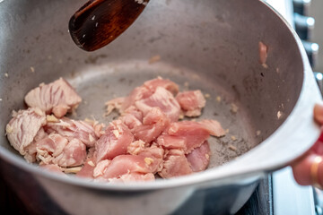 Unidentifiable chef frying off lean chicken pieces in a pan to make a home cooked chicken stir fry for dinner. Selective focus, shallow depth of field and bokeh