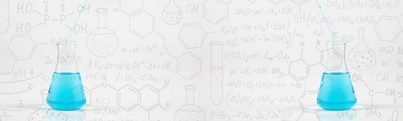 A studio photo of a Erlenmeyer Flask,Hand drawn science formulas on chalkboard for...
