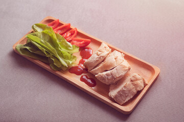 Top view of chicken boiled with vegetables served on wooden plate on  gray cloth background