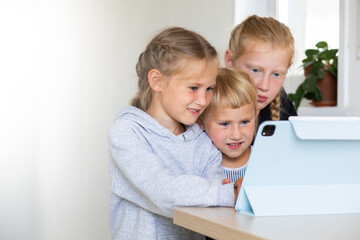 A little preschooler girls watches cartoons on a tablet in a network room, distance education during a pandemic, the children learns high technologies