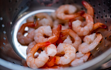 Close and selective focus on raw king prawns in a colander being cleaned and rinsed to make a home made prawn curry