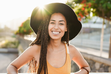Young mixed race woman smiling in camera outdoor with sunset in the background