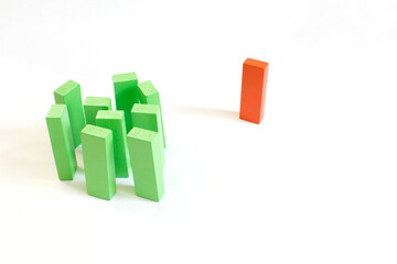 Orange block standing alone away from green wooden blocks, exclusion concept.