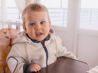 A one-year-old caucasian girl looks very affably at the photographer