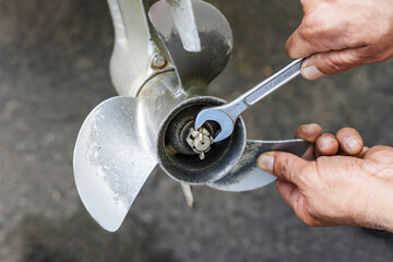 The process of replacing a boat propeller with a wrench. The technician unscrews the screw from the...