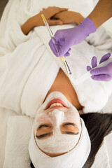 Mujer mexicana felizmente  relajada tomando un tratamiento de cuidado exfoliante de piel