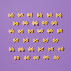 Fototapeta na wymiar Creative layout of homemade farfalle. Fun and bright food concept. Italian pasta on purple background.