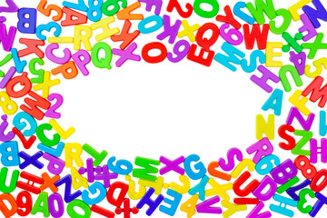 Background from multi colored plastic letters and numbers in a chaotic manner on a white backdrop. Place for text in the form of an oval. Copy space. English alphabet. Children school developmental co