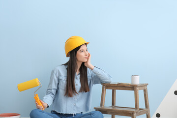 Young woman with paint roller on color background