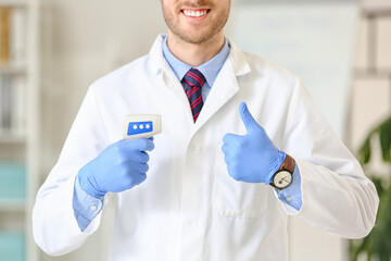 Doctor with infrared thermometer showing thumb-up in clinic