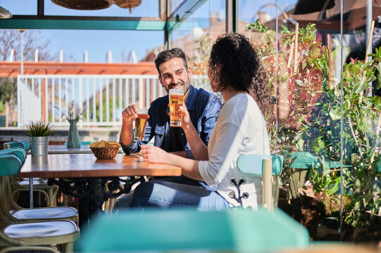 Smiling ethnic couple with beer spending weekend in restaurant