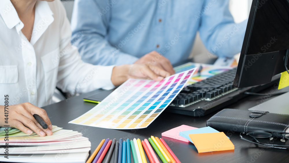 Poster graphic designer or creative working together coloring using graphics tablet and a stylus at desk wi