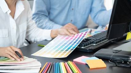 Graphic designer or creative working together coloring using graphics tablet and a stylus at desk...