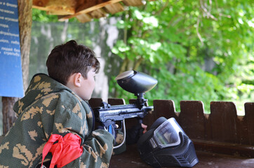 A boy aims at a target with a paintball marker.