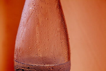 Stylized grungy red closeup of plastic bottle with condensation water droplets