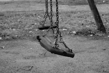 Ruined seats of an old abandoned swing.
Black and white photo of an old abandoned playground. Melancholy childhood memories. Seats hung with chains ruined by time.