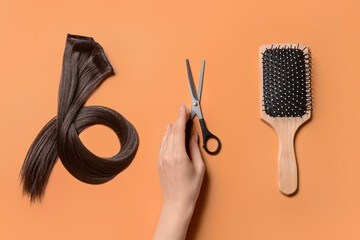 Woman with strand of brown hair, scissors and comb on color background