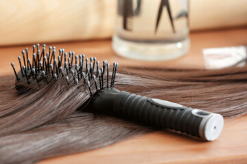 Brush with hair strands on table in beauty salon, closeup