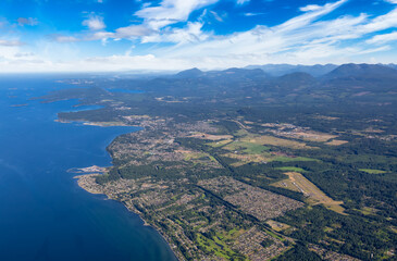 Fototapeta premium Aerial View of Qualicum Beach from an Airplane on the shore of Strait of Georgia in Vancouver Island, British Columbia, Canada. Colorful Blue Sky Art Render.