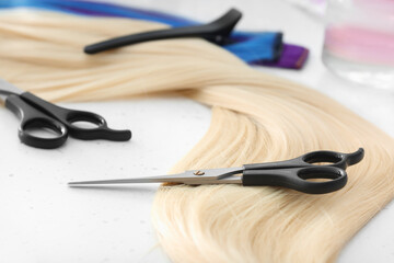 Strand of blonde hair with scissors on table, closeup