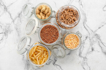 Glass jars with different products on light background