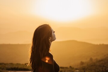 Carefree woman standing on hill and enjoying freedom