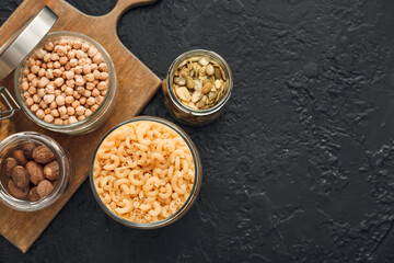 Glass jars with different products on dark background