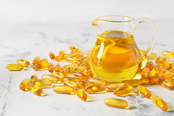 Jug with fish oil and pills on light background