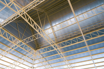 View from below of metal warehouse building roof structure with heat insulations inside of construction site