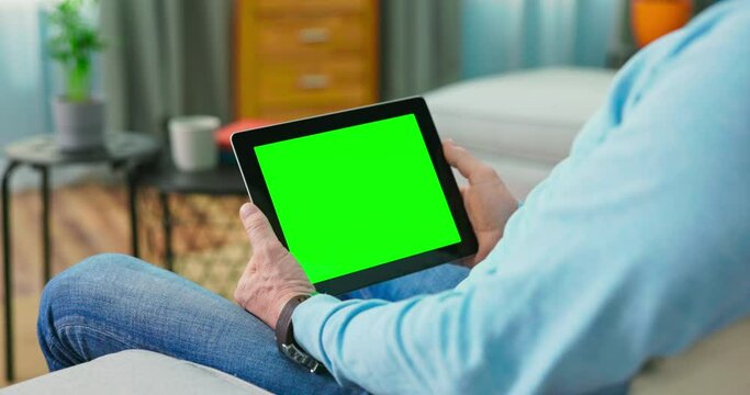 Man watching series with on demand video website concept. Streaming digital film from site by tv network. Close up of digital tablet with blank green mock up Screen display
